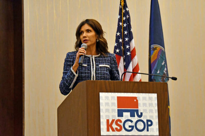 Kristi Noem speaking at KS GOP event podium.