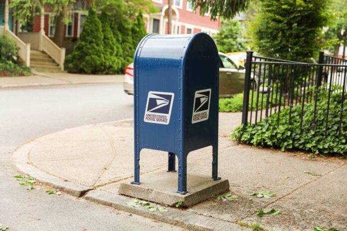 Blue USPS mailbox on a residential street corner.