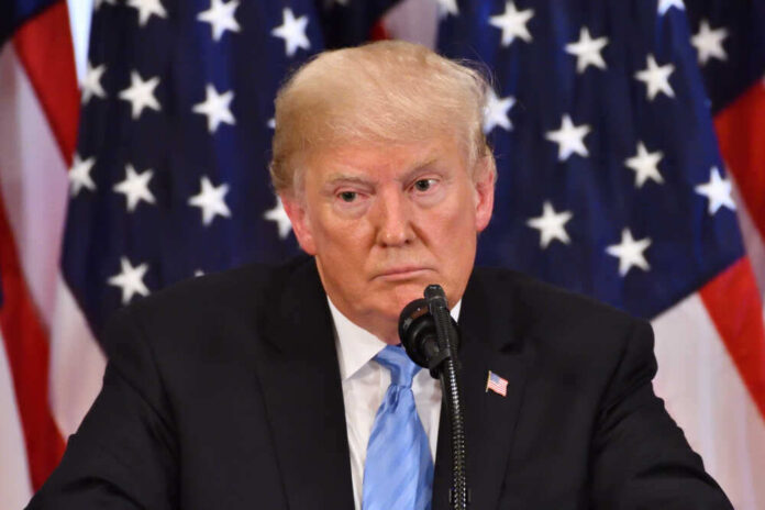 shutterstock_1191272251.jpg featured image Donald Trump speaking with American flags in background.