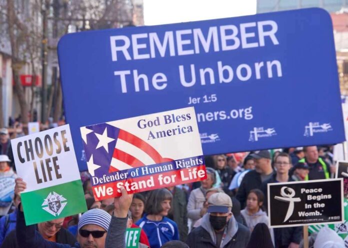 shutterstock_2252807065.jpg featured image Pro-life marchers holding various anti-abortion signs.