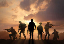 Soldiers silhouetted against a sunset, holding weapons.