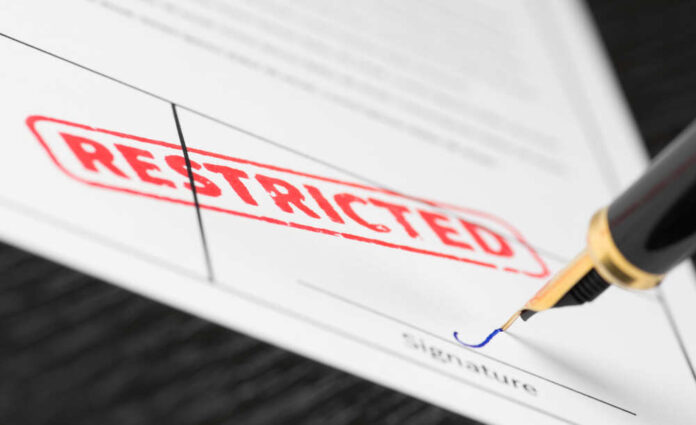 shutterstock_1144717307.jpg featured image Document labeled restricted with pen signing signature line