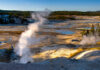 Geysers emitting steam in Yellowstone National Park landscape