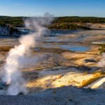 Geysers emitting steam in Yellowstone National Park landscape