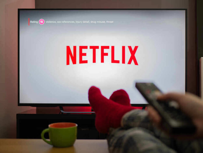 shutterstock_1683498799.jpg featured image Person watching Netflix with remote and drink.