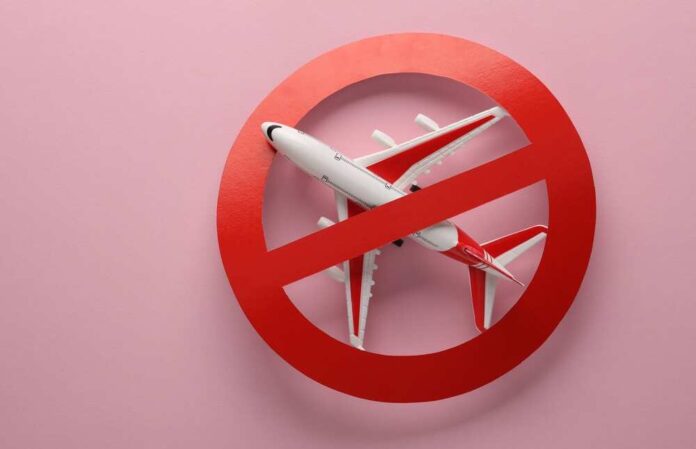 shutterstock_2273482921.jpg featured image Airplane inside red prohibition sign on pink background.