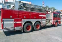 Red fire truck with ladder parked outside building