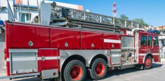 Red fire truck with ladder parked outside building