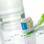 Toothbrush with toothpaste near glass of water