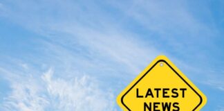 Yellow sign with latest news text against sky