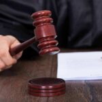 Wife SENTENCED – Masterminded Husband’s Murder! Judge's hand holding gavel next to documents.