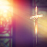 200 Christians KILLED in Brutal Attack Crucifix with sunlight, stained glass window in background.