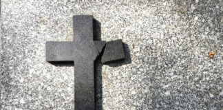 Broken black cross on a gray surface.