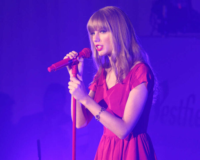 shutterstock_147305117.jpg featured image Taylor Swift in a red dress performing on stage.
