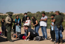 Group of people talking to border patrol officer.