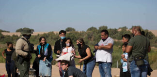 Group of people talking to border patrol officer.
