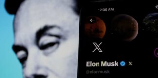 Elon Musk's profile on mobile screen, blurred background face.
