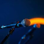 Close-up of a microphone on a stand, dark background.