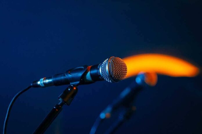 Close-up of a microphone on a stand, dark background.