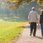 Older Americans LIGHTING UP? – Usage SKYROCKETS! Two people walking together on a park path.