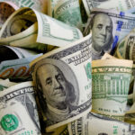 BOMBSHELL: 1,000 New Millionaires PER DAY! Rolled U.S. dollar bills in various denominations.