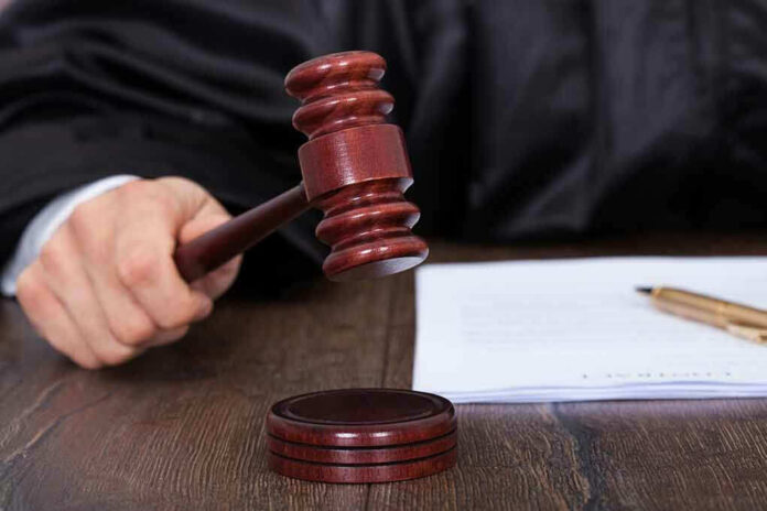 186812807 Judge's hand holding gavel next to documents.