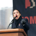 Alexandria Ocasio-Cortez passionately speaking at a podium outside