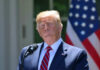 Donald Trump speaking with US flag in the back