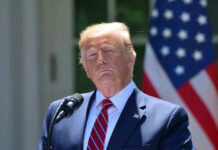 Donald Trump speaking with US flag in the back