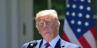 Donald Trump speaking with US flag in the back