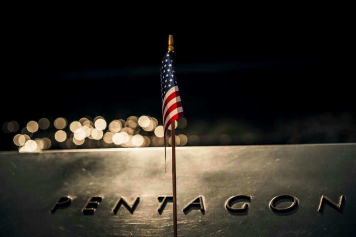 shutterstock_2321355077.jpg American flag above engraved Pentagon sign at night