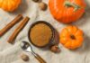 A bowl of pumpkin spice surrounded by pumpkins and cinnamon sticks