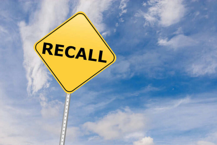 Yellow sign with RECALL text against blue sky