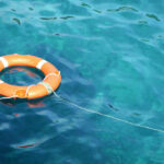 Orange life ring floating in clear blue water