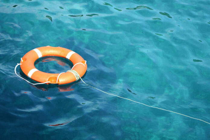 Orange life ring floating in clear blue water