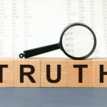 Wooden blocks spelling truth with magnifying glass