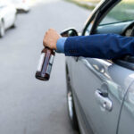 Arm holding beer bottle outside car window