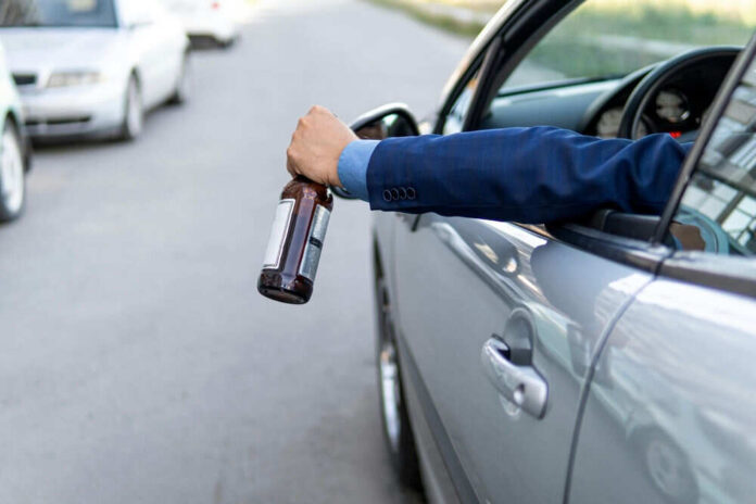 Arm holding beer bottle outside car window