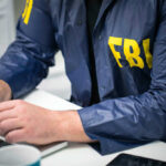 Person in FBI jacket working on laptop