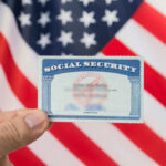 SOCIAL SECURITY CHAOS: Changes Just Days Away Hand holding social security card, American flag background