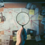 Magnifying glass over investigation board with photos and strings