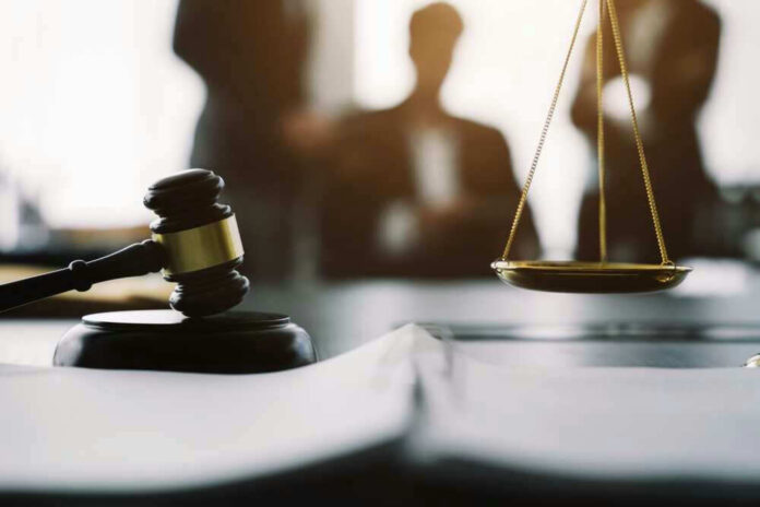 Gavel and scales in courtroom with blurred figures behind