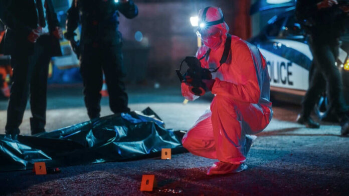 Forensic investigator examines crime scene at night