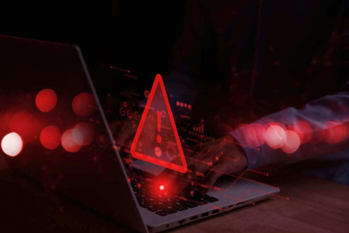 shutterstock_2248466625.jpg Warning symbol over laptop with user