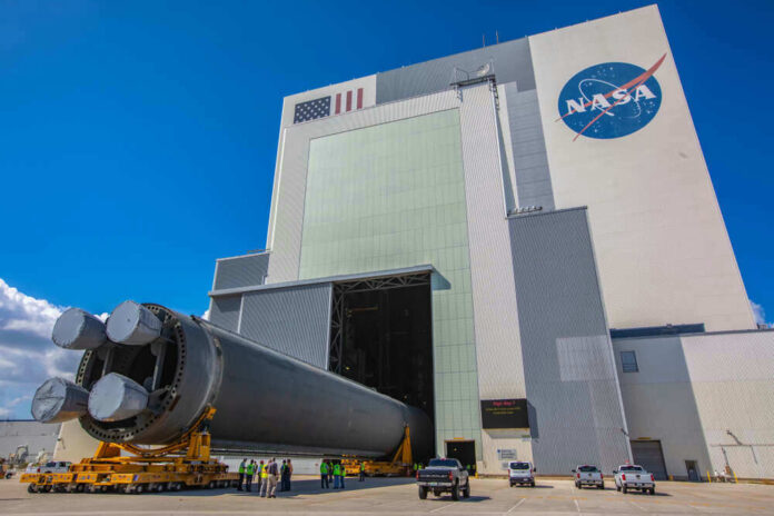 Massive rocket component outside NASA assembly building under clear sky