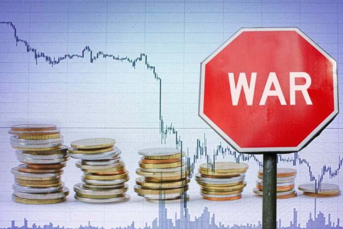 A stop sign with the word 'WAR' in front of a declining stock market graph and stacks of coins