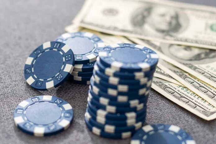 Stack of blue poker chips next to cash bills