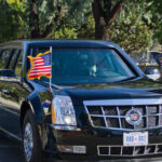 Trump Motorcade Takes Evasive Action A black limousine with flags driving in a motorcade