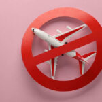 Airplane inside red prohibition sign on pink background.