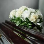 Reggae Icon’s Death Saddens Music World A floral arrangement of white roses and greenery on a polished casket